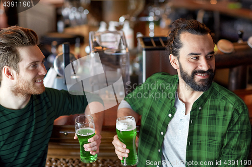 Image of male friends drinking green beer at bar or pub