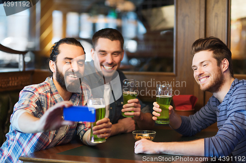 Image of friends taking selfie with green beer at pub