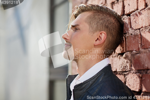 Image of portrait of man in leather jacket over brick wall