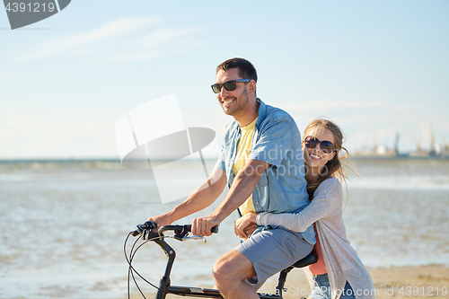 Image of happy young couple riding bicycle on beach