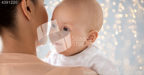 Image of close up of happy baby with mother over lights