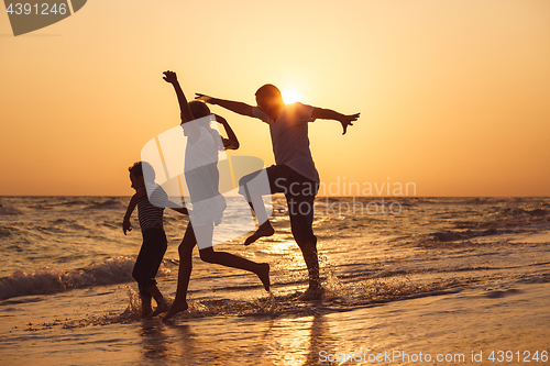 Image of Father son and daughter playing on the beach at the sunset time.