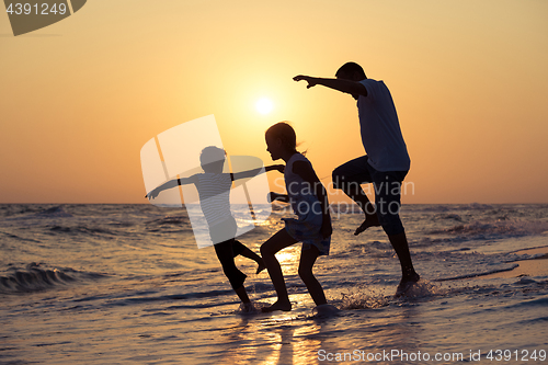 Image of Father son and daughter playing on the beach at the sunset time.