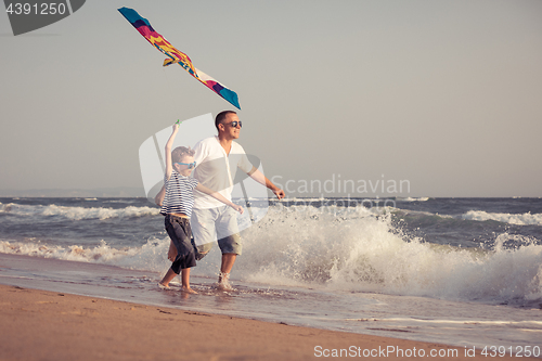 Image of Father and son playing on the beach at the day time.