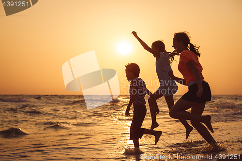 Image of Happy children playing on the beach at the sunset time.