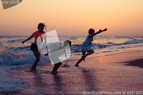 Image of Happy children playing on the beach at the sunset time.