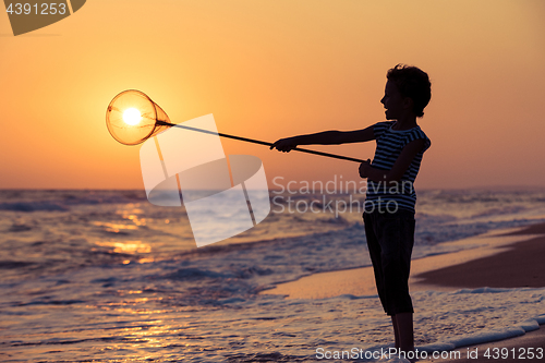 Image of One happy little boy playing on the beach at the sunset time.