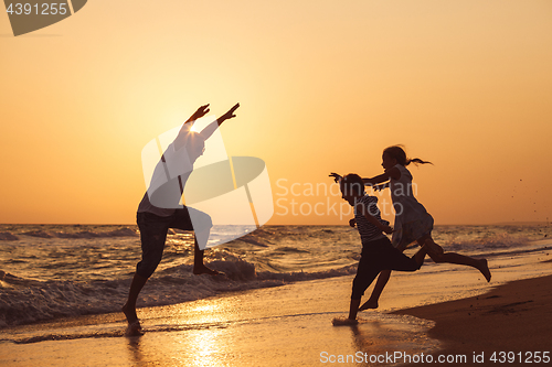 Image of Father son and daughter playing on the beach at the sunset time.