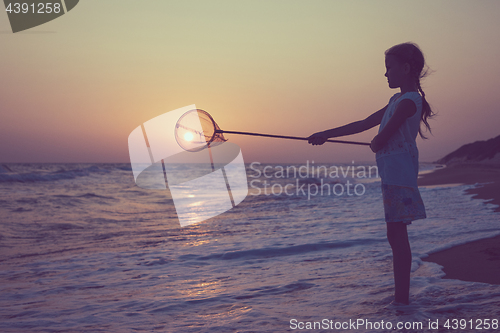 Image of One happy little girl playing on the beach at the sunset time.