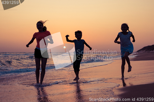 Image of Happy children playing on the beach at the sunset time.