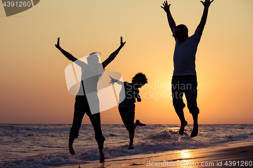 Image of Father mother and  son  playing on the beach at the sunset time.