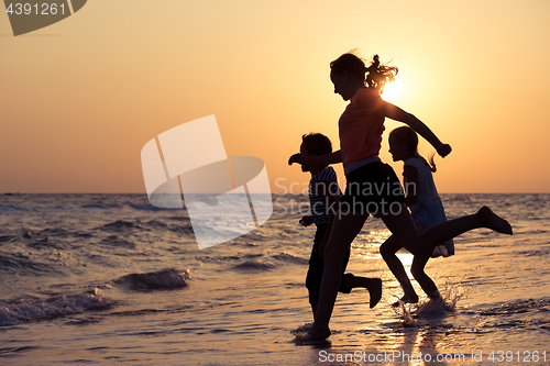 Image of Happy children playing on the beach at the sunset time.