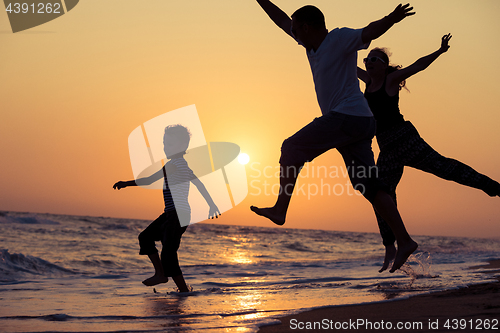 Image of Father mother and  son  playing on the beach at the sunset time.