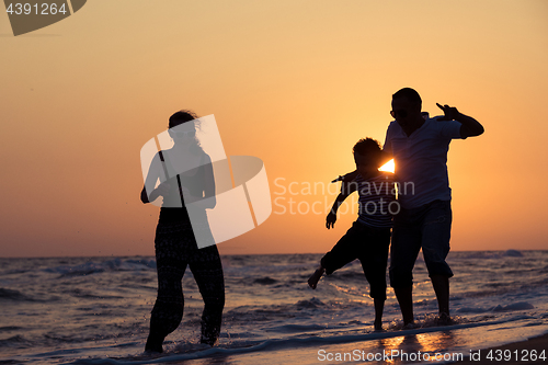 Image of Father mother and  son  playing on the beach at the sunset time.