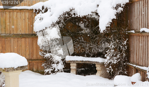 Image of Stone bench covered in snow in a country garden