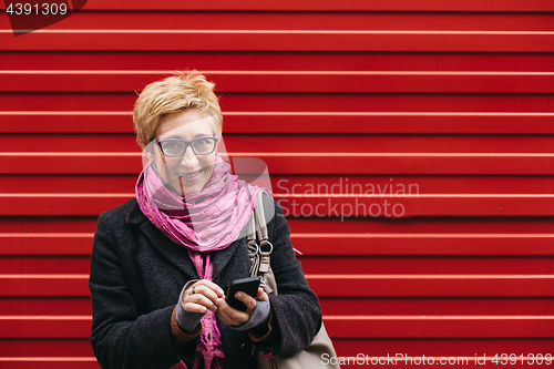 Image of Smiling adult woman with smartphone