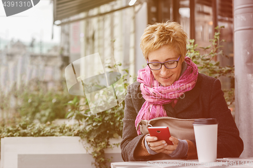 Image of Smiling woman with phone in cafe