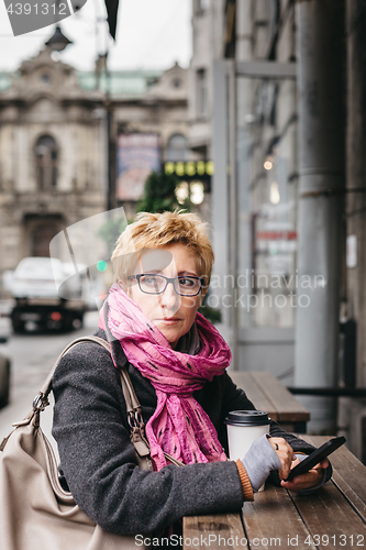 Image of Woman with smartphone looking away