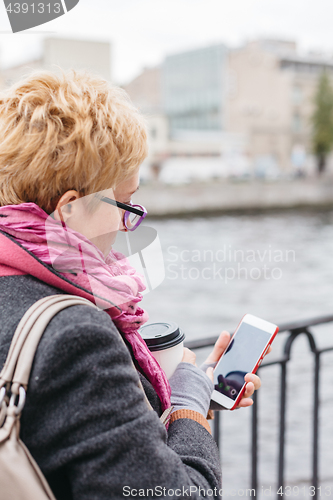 Image of Woman using smartphone at river