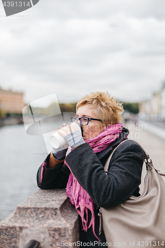 Image of Woman drinking coffee on waterfront