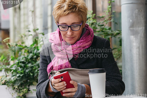 Image of Smiling woman with phone in cafe