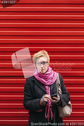 Image of Woman with phone at red fence