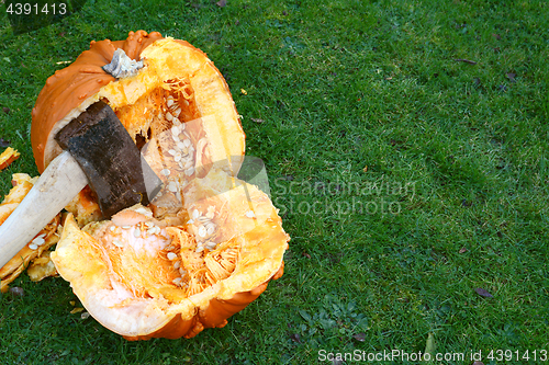Image of Axe hacks a large orange pumpkin in half
