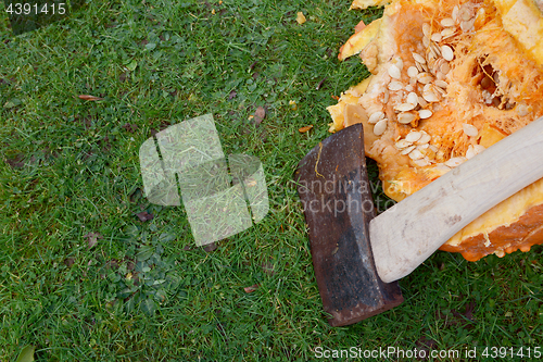 Image of Sharp axe against a large pumpkin, hacked open