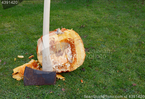 Image of Axe against large pumpkin, roughly cut in half
