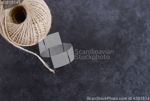 Image of Ball of twine from above, unwinding on grey background 