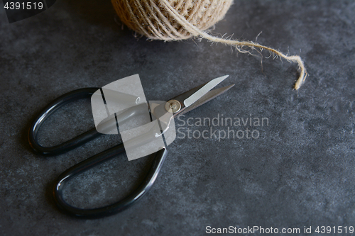 Image of Scissors with rough twine on a grey tile background 