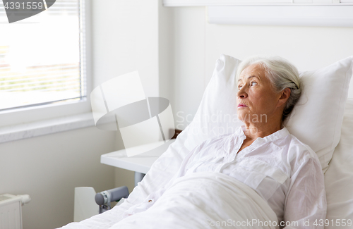 Image of sad senior woman lying on bed at hospital ward