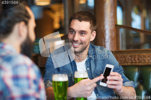 Image of friends with smartphone drinking green beer at pub