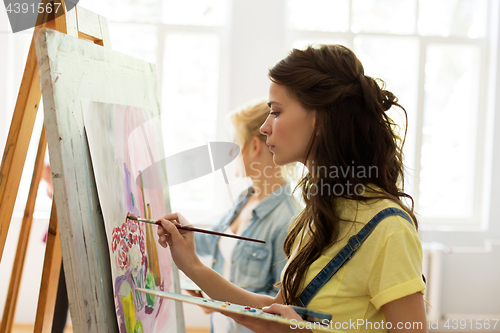 Image of woman with easel painting at art school studio