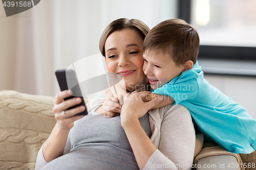 Image of pregnant mother and son with smartphone at home