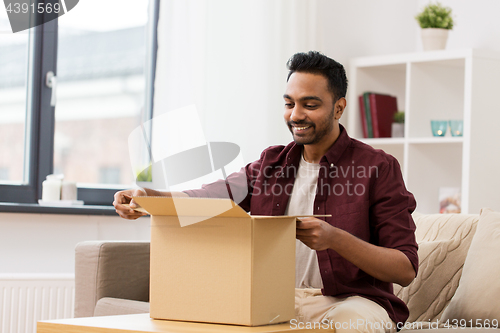 Image of happy man opening parcel box at home