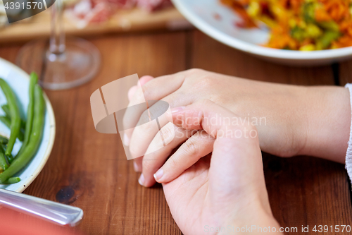 Image of hands of people at table praying before meal