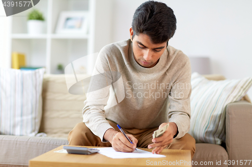 Image of man with money and calculator filling papers