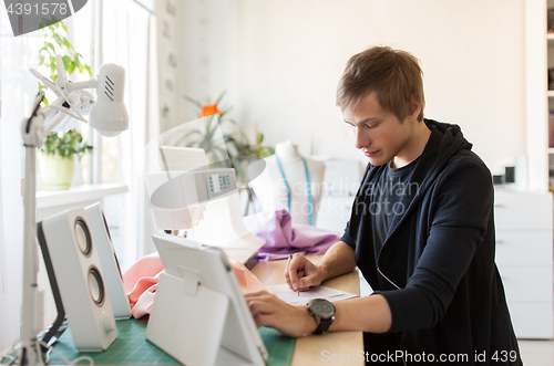 Image of fashion designer with tablet pc working at studio