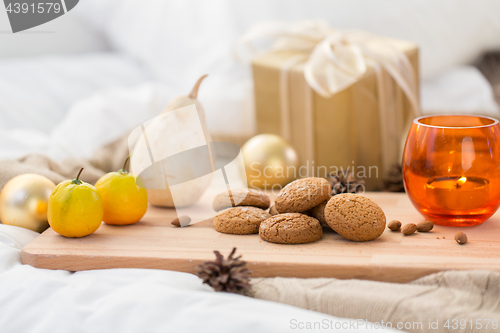 Image of cookies, lemon, candle and christmas gift at home