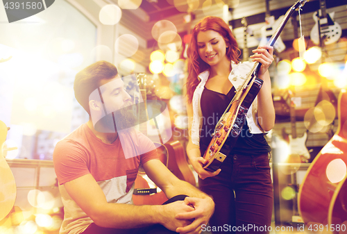 Image of couple of musicians with guitar at music store