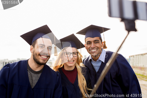 Image of happy students or graduates taking selfie outdoors
