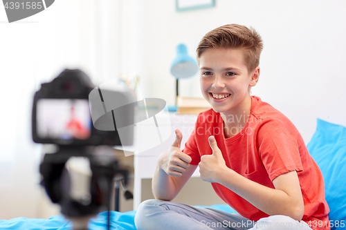 Image of happy boy with camera recording video at home