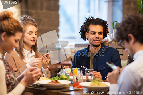 Image of friends with smartphones at bar or restaurant