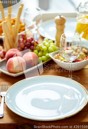 Image of empty plate and wine glass on table with food