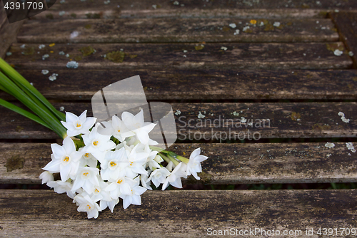 Image of Bunch of white narcissi flowers on a rustic bench