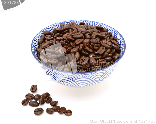 Image of Roasted coffee beans in a bowl, some spilled beside