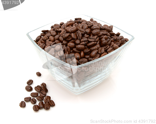 Image of Glass dish filled with coffee beans, some spilled beside