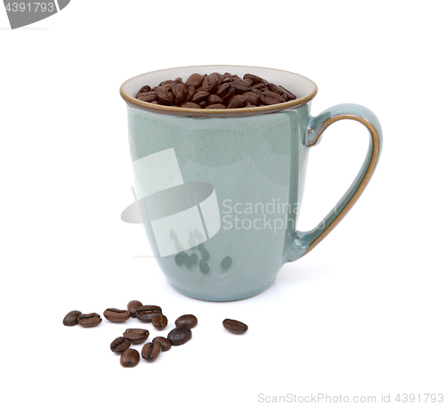 Image of Coffee beans in green mug and spilled beside