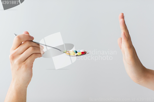 Image of close up of female hand holding spoon with pills